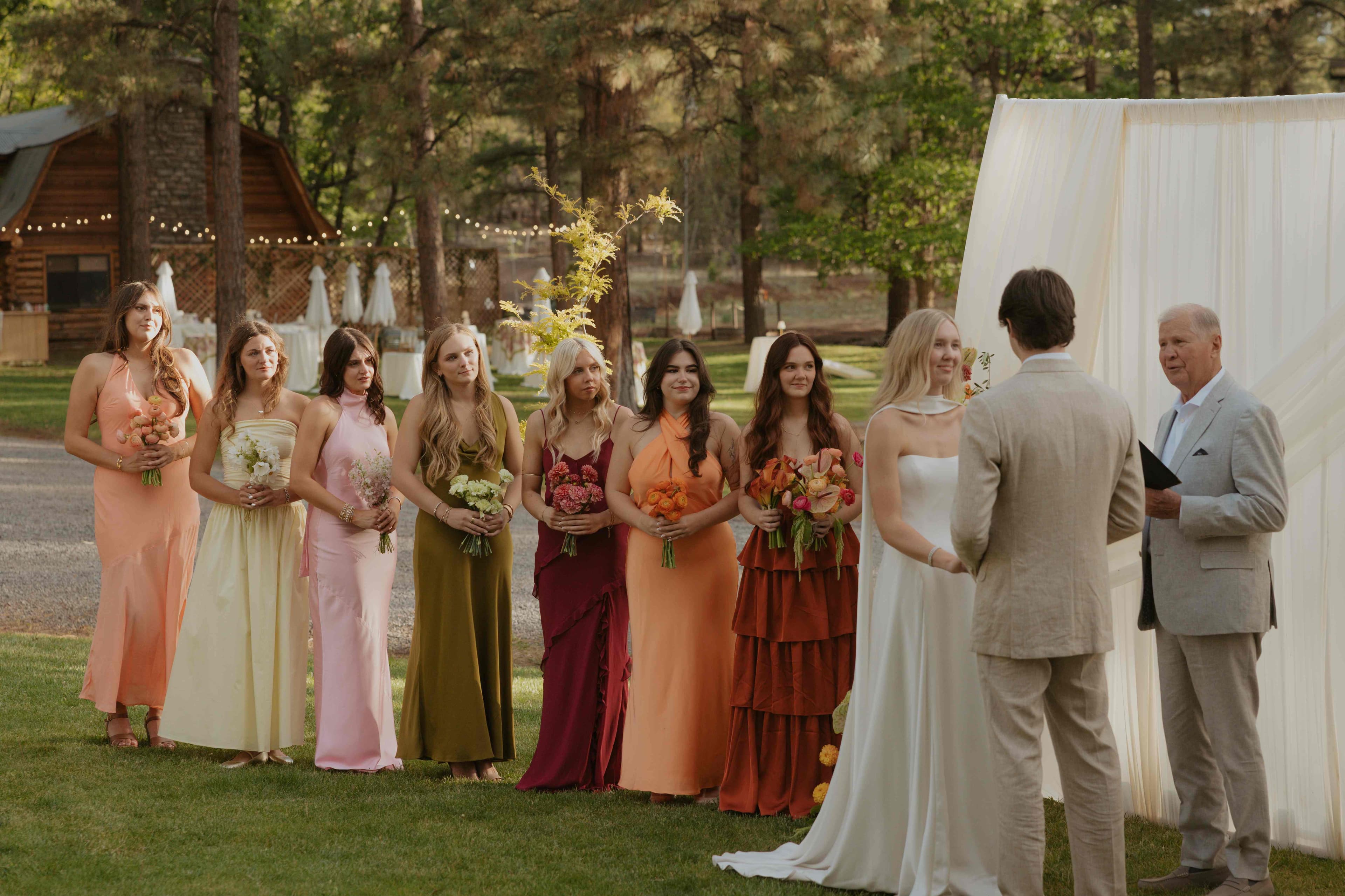 Bridesmaids in colorful dresses lined up beside the bride, groom, and officiant during the ceremony
