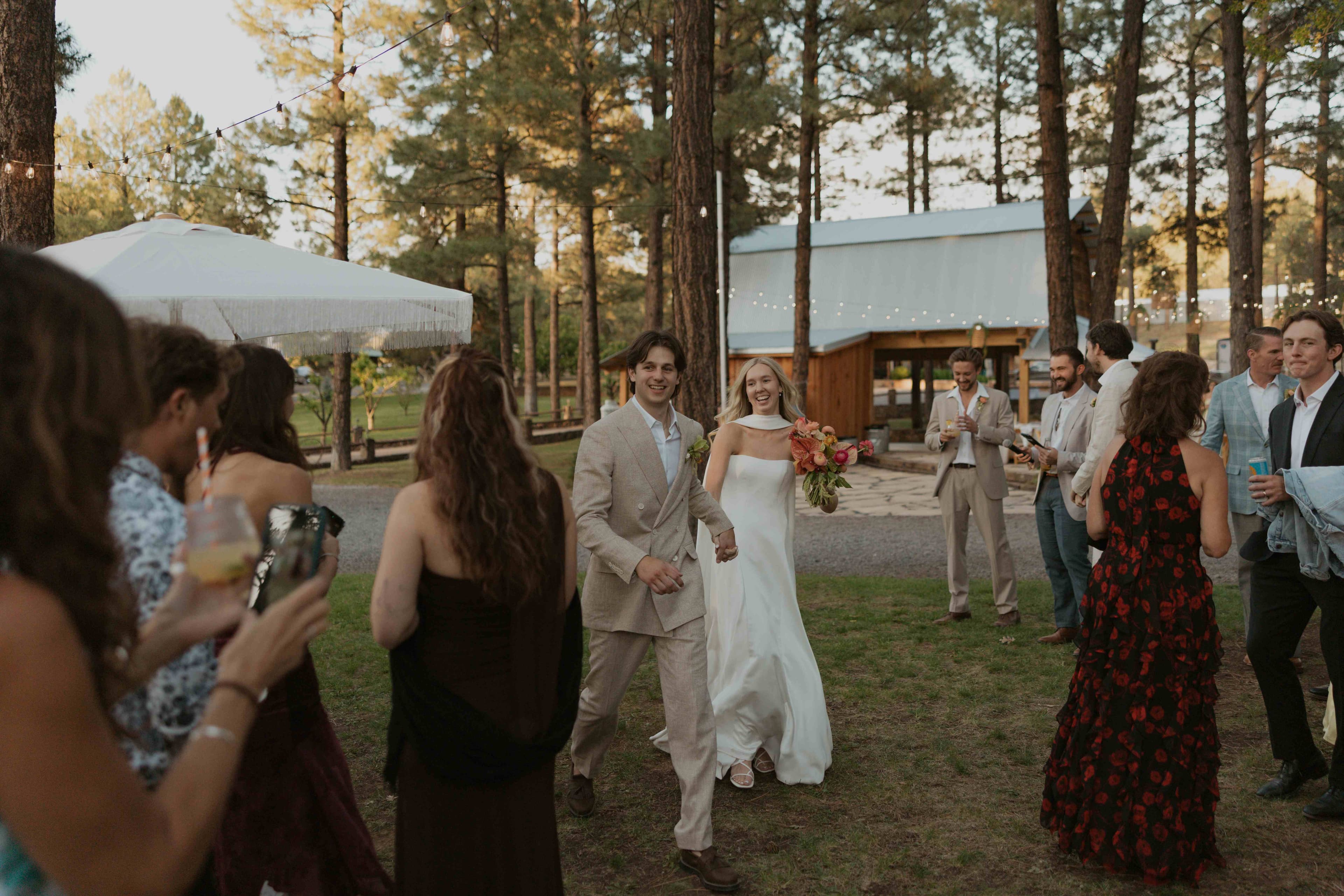 Bride and groom walking hand in hand through cheering guests during cocktail hour